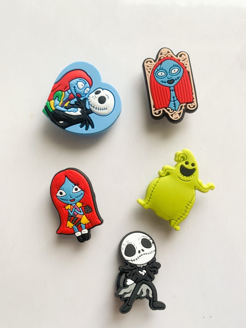 Puede incluir: Colecci&oacute;n de cinco coloridos dijes para zapatos con personajes de "Pesadilla antes de Navidad". Incluye a Jack Skellington, Sally y Oogie Boogie, en varias poses y dise&ntilde;os. Los dijes est&aacute;n hechos de goma o material similar.