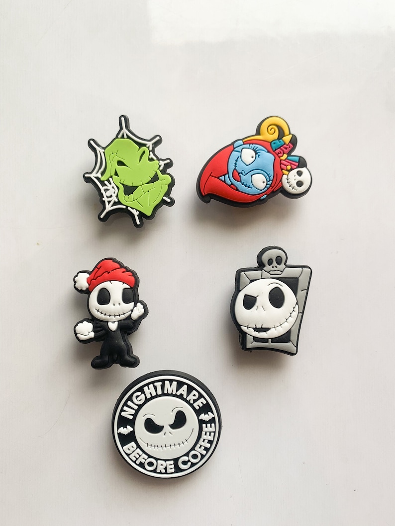 Puede incluir: Una colecci&oacute;n de coloridos dijes para zapatos con personajes de "Pesadilla antes de Navidad". Incluye a Oogie Boogie, Sally, Jack Skellington y un dije con el texto "Nightmare Before Coffee."