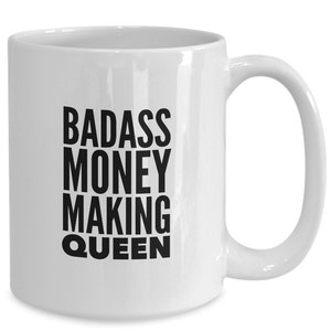 May include: White ceramic coffee mug with black text that reads "BADASS MONEY MAKING QUEEN".