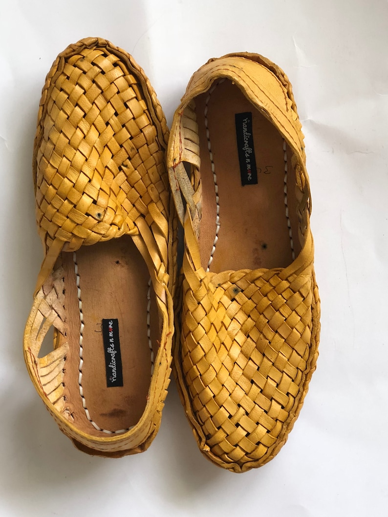 May include: A pair of yellow woven leather sandals with a label that reads "handicrafts in me."