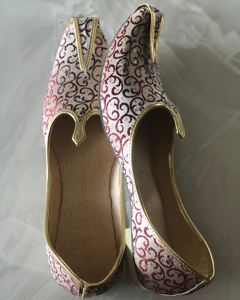May include: A pair of white and burgundy patterned shoes with gold trim. The shoes have a pointed toe and a closed back.