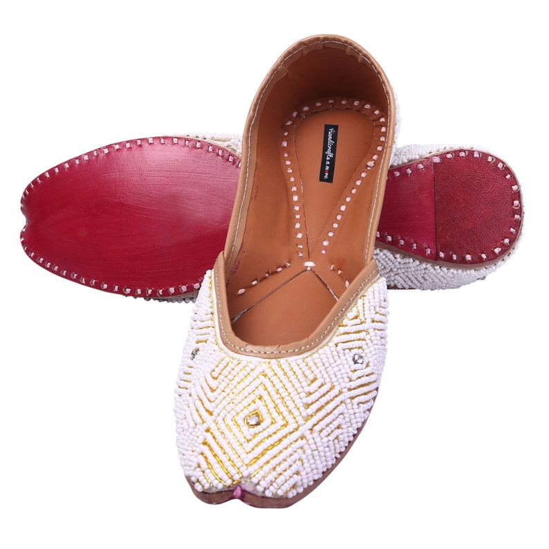 May include: White beaded flat shoes with gold embroidery and a diamond-shaped design. The shoes have a pointed toe and a low heel.