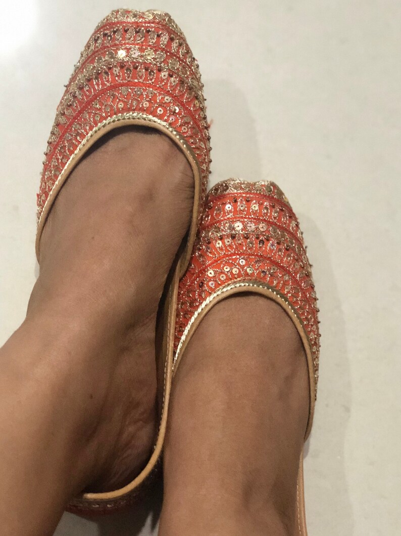 May include: A pair of orange and gold embroidered flat shoes with sequins.
