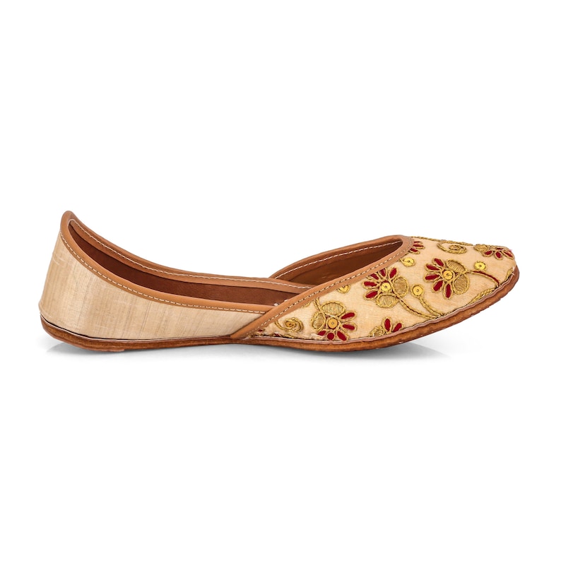 May include: Beige embroidered flat shoes with red and gold floral designs.