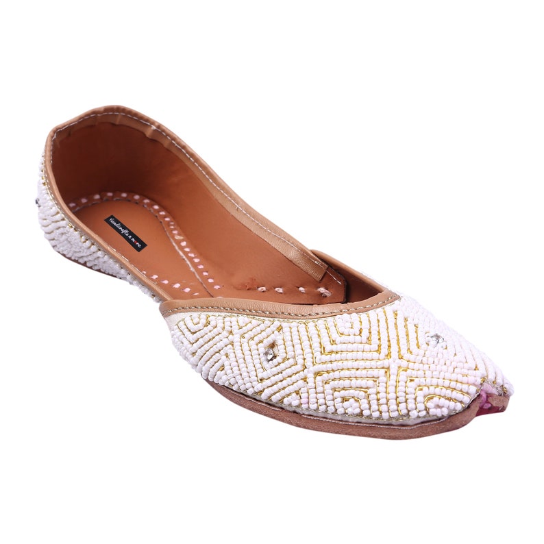 May include: White beaded flat shoes with a geometric pattern. The shoes have a brown leather insole and a pink trim.