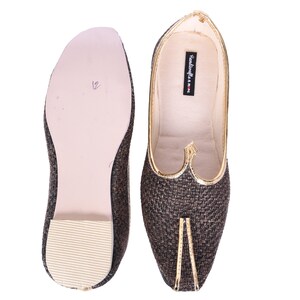 May include: A pair of brown woven fabric shoes with gold trim. The shoes have a pointed toe and a flat sole. The shoes are made by "Handicrafts of India".