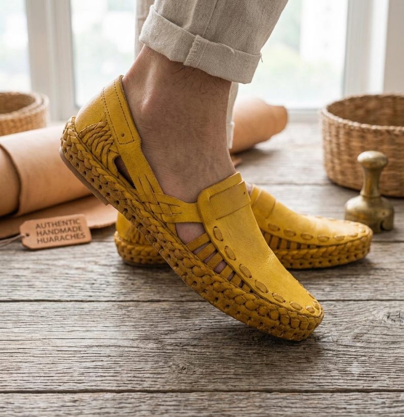 May include: A pair of yellow leather huarache shoes featuring a woven design, cut-out side panels, and a thick braided sole. A small rectangular tag nearby displays the text AUTHENTIC HANDMADE HUARACHES in black capital letters.
