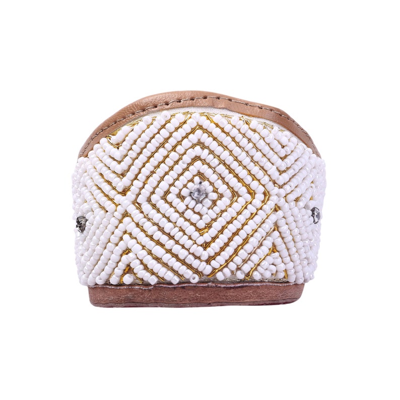May include: A pair of white beaded flats with a brown leather strap. The beads are arranged in a geometric pattern.