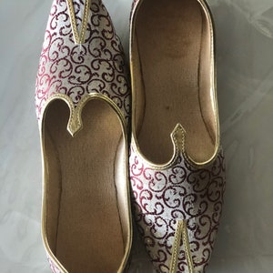 May include: A pair of red and gold embroidered flat shoes with pointed toes.