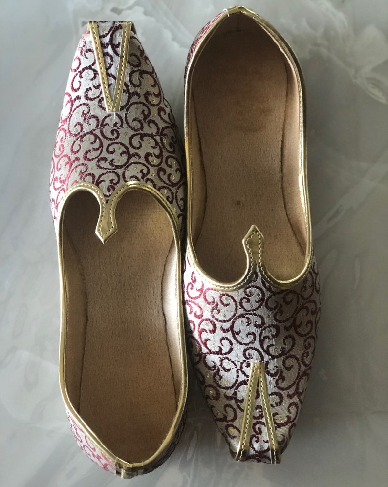 May include: A pair of red and gold embroidered flat shoes with pointed toes.