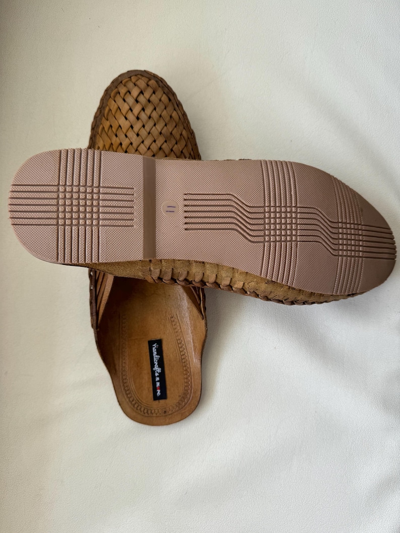 May include: A pair of brown woven leather sandals. The sandals have a textured sole and a woven upper design. The sole is a light brown color, and the upper is a darker brown. The sandals are designed for casual wear.