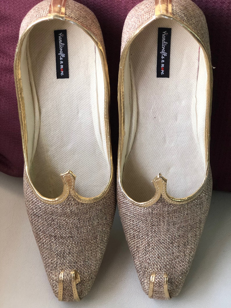 K&ouml;nnte beinhalten: Ein Paar goldene und braune Stoffschuhe mit spitzer Zehenpartie und goldener Verzierung. Die Schuhe haben den Text "handicrafts in me" auf der Innenseite.