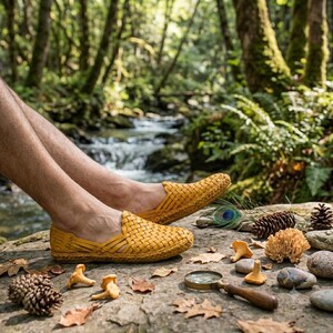 May include: A pair of mustard yellow woven slip-on shoes featuring a crisscross leather pattern, a rounded toe, and a flat sole. The shoes are constructed with a flexible, interlaced design that covers the top of the foot and the heel area.