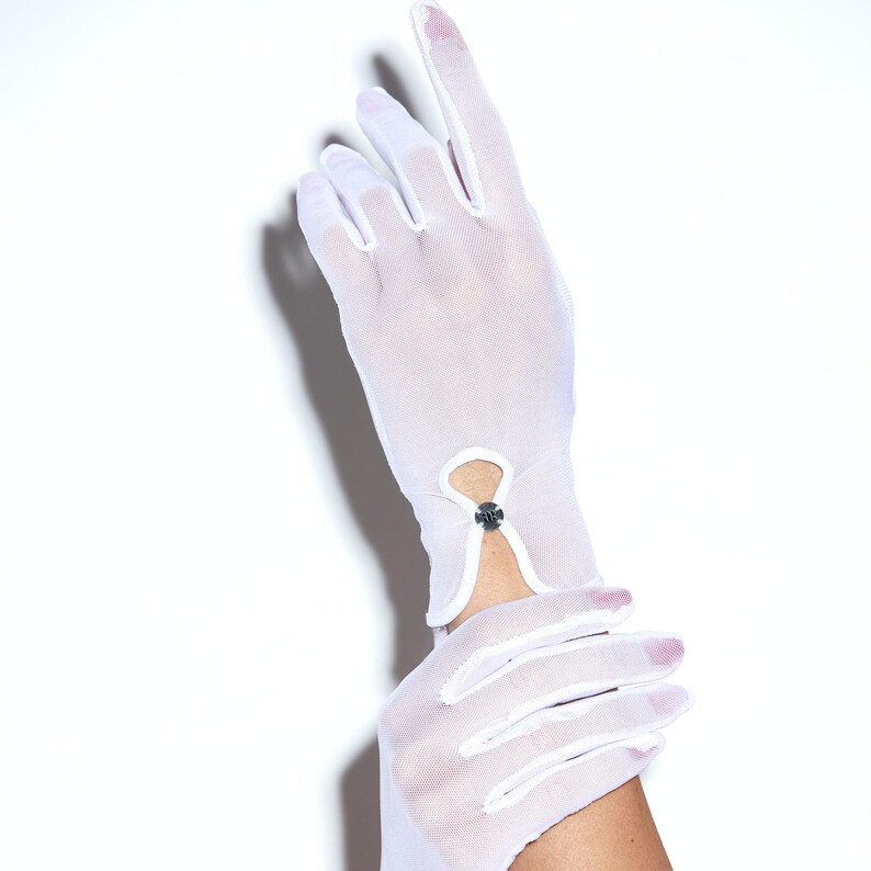 Puede incluir: Un par de guantes de malla blanca con un detalle de bot&oacute;n en la mu&ntilde;eca.
