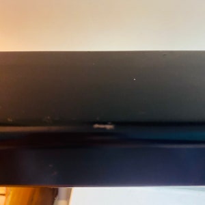 May include: Close-up of a black metal shelf with a slight scratch on the surface.