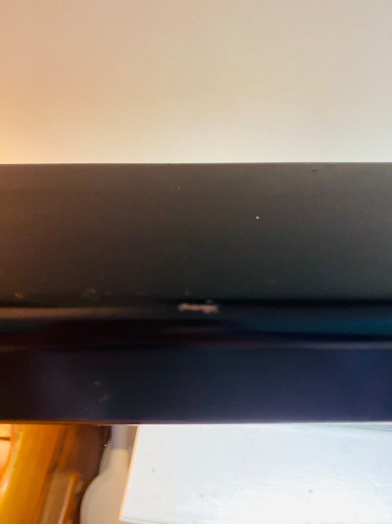 May include: Close-up of a black metal shelf with a slight scratch on the surface.