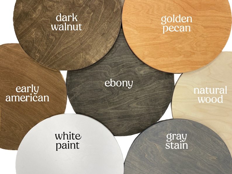 K&ouml;nnte beinhalten: Sechs runde Holzscheiben, jede in einer anderen Farbe lackiert und mit einer Holzbeize oder -farbe beschriftet. Die Farben sind: Dunkelwalnuss, Goldene Pecan, Ebenholz, Naturholz, Wei&szlig;lack und Graubeize.
