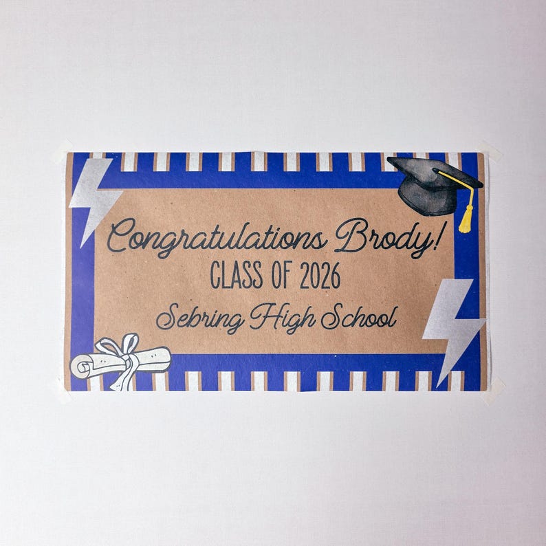 May include: A graduation card with a brown background and blue border. The card says "Congratulations Brody! CLASS OF 2026 Sebring High School". It features a graduation cap, lightning bolts, and a diploma illustration.