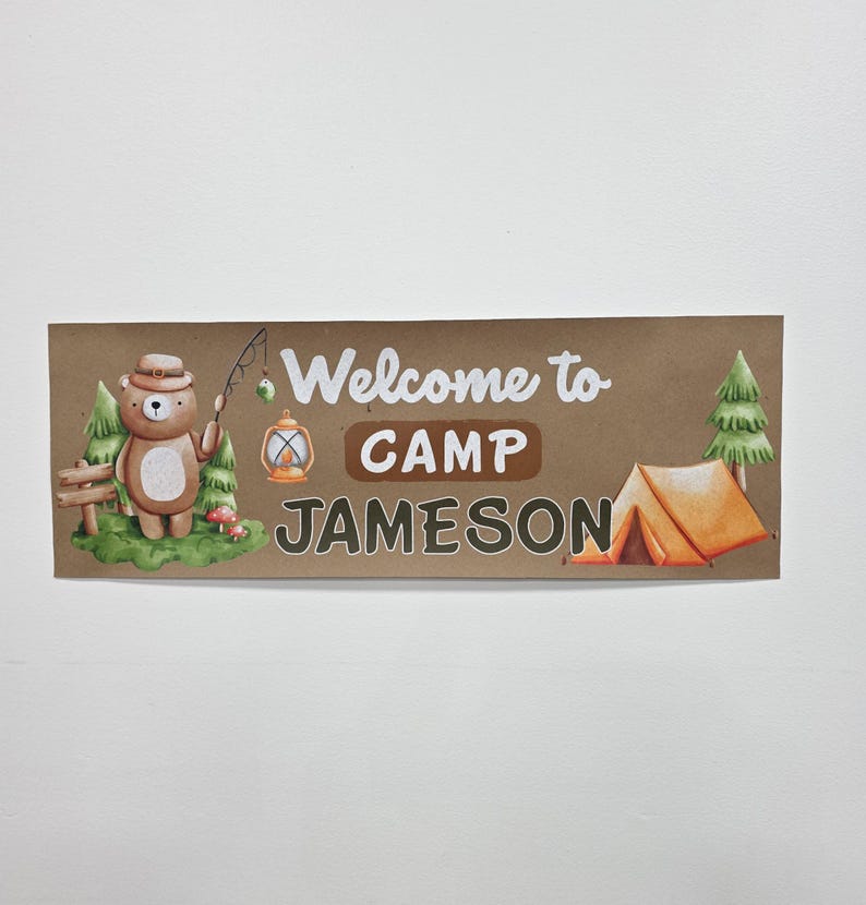 May include: A rectangular sign with a brown background features the text "Welcome to CAMP JAMESON." A cartoon bear with a hat and fishing rod stands near a fence and trees. An orange tent and lantern are also depicted.