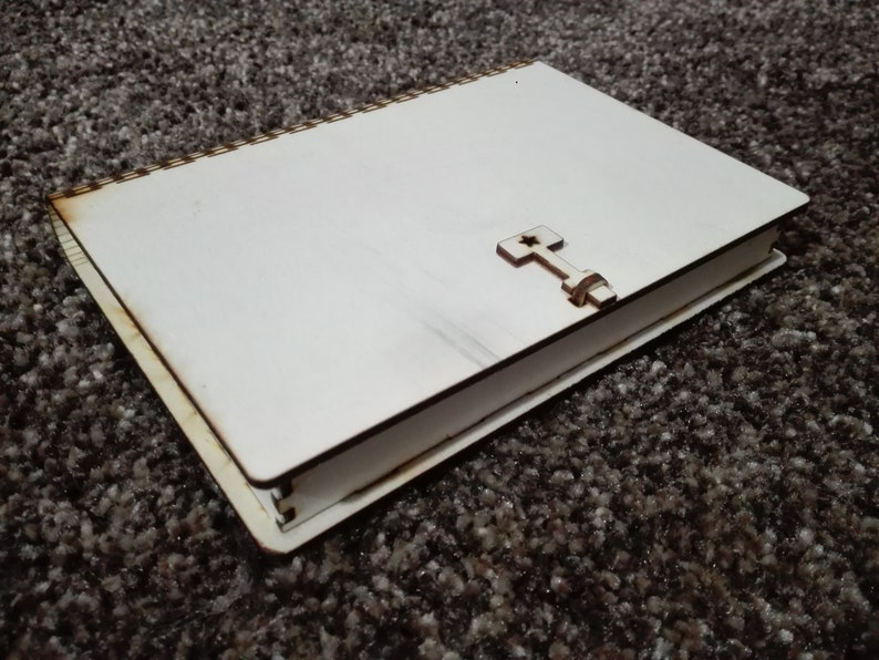 Peut inclure: Un journal en bois blanc avec un motif de croix en bois sur la couverture. Le journal a une reliure spirale et est ferm&eacute;.