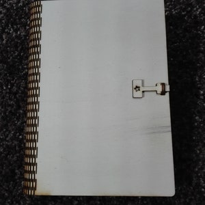 Peut inclure: Une bo&icirc;te en bois blanche avec une bordure &agrave; motif brun et un petit loquet en m&eacute;tal. La bo&icirc;te est ferm&eacute;e.