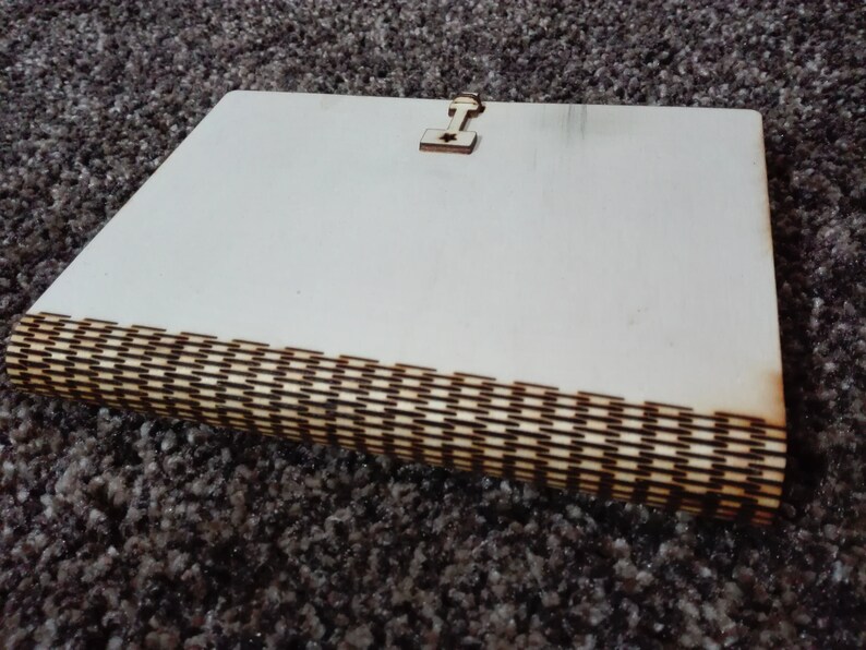 Peut inclure: Un journal en bois blanc avec une incrustation d&eacute;corative en bois sur le bord. Le journal a un petit fermoir en bois sur le devant.