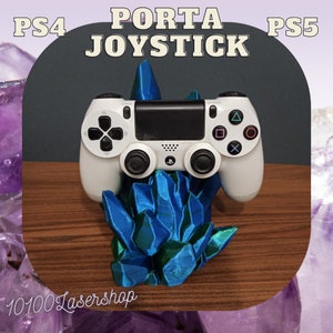 Könnte beinhalten: Ein weißer PS4/PS5-Controller liegt auf einem blau-grünen Kristall-Ständer. Der Ständer hat einen Farbverlauf, mit dem Text "PORTA JOYSTICK" über dem Controller. Das Bild ist vor einem dunklen Hintergrund mit dem Text "PS4" und "PS5" platziert.