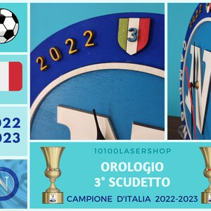 May include: A wooden clock with a blue face, featuring the number "3" on a shield with Italian flag colors. The clock also displays the text "2022" and "2023" in gold. A soccer ball and the Italian flag are also shown.