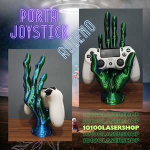 Op de afbeelding: Een 3D-geprinte groene en blauwe alienhand die een witte PlayStation 4-controller vasthoudt. De hand houdt de controller op een ontspannen, bijna nonchalante manier vast. De hand is gemonteerd op een zwarte basis. De tekst "10100LASERSHOP" wordt meerdere keren herhaald op de achtergrond.