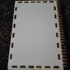 Peut inclure: Une bo&icirc;te en bois blanc avec une bordure en bois brun. La bo&icirc;te a un motif d&eacute;coratif sur le c&ocirc;t&eacute;.