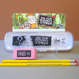 May include: A clear plastic pencil case, pink eraser, and two yellow pencils with the text "MY GYM PARTNER'S A MONKEY" and "PROPERTY OF CHARLES DARWIN MIDDLE SCHOOL". A ruler and cartoon characters are also visible.