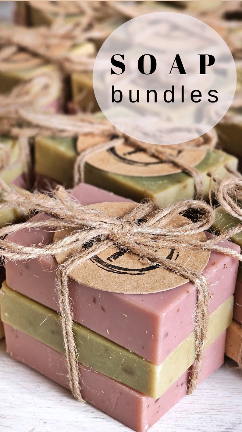 K&ouml;nnte beinhalten: Ein Set aus drei handgefertigten Seifen, zwei gr&uuml;n und eine rosa, die mit Schnur und einem braunen Papieretikett zusammengebunden sind. Das Etikett hat einen Stempel mit der Aufschrift "SOAP bundles".