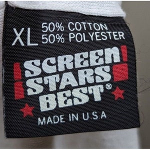 May include: Black tag with white text that reads "XL 50% Cotton 50% Polyester SCREEN STARS BEST" with two red stars and a red square. The tag also reads "Made in U.S.A."