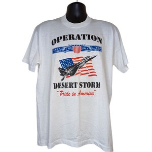 May include: White t-shirt with a black print of an F-16 fighter jet flying over an American flag. The text "Operation Desert Storm" and "Pride in America" are printed below the image.