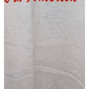 May include: White cotton t-shirt with a red stain.