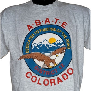 May include: A gray t-shirt with a blue and red circular logo featuring a bald eagle, mountains, and the text "A*B*A*T*E Dedicated to Freedom of the Road Colorado District 12".