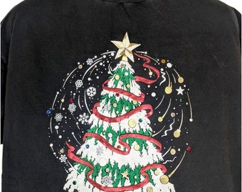 Puede incluir: Camiseta negra con un diseño festivo de árbol de Navidad. El árbol está decorado con una cinta roja, adornos dorados y copos de nieve blancos. El fondo es negro con un patrón de remolino de copos de nieve blancos.