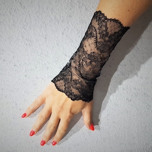 Peut inclure: Manchette de poignet en dentelle noire avec un motif floral délicat.