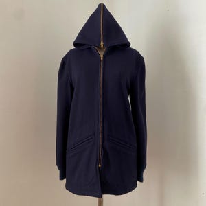 May include: A navy blue hooded sweatshirt with a full-length brass zipper and two front pockets. The hood is pointed and the cuffs are ribbed. The sweatshirt is made of a soft, medium-weight fabric.