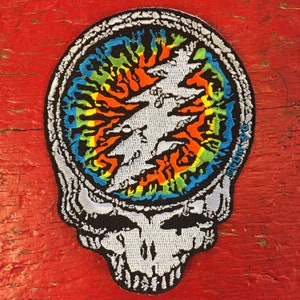 May include: A colourful tie-dye Grateful Dead Steal Your Face patch with a white skull and crossbones design.