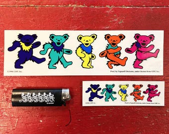May include: A sheet of colorful stickers featuring five cartoon bears with different colored fur and clothing. The bears are all smiling and have a playful expression. The stickers are printed on white paper and have a glossy finish. The text on the sticker sheet reads "Prod. by Yujean Stickems, under license from GDP, Inc."