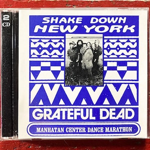 Könnte beinhalten: Eine CD-Hülle mit dem Album "Shake Down New York" von The Grateful Dead. Das Cover ist blau und weiß mit dem Namen der Band und einem Foto der Bandmitglieder. Der Text "Manhattan Center Dance Marathon" ist ebenfalls vorhanden.