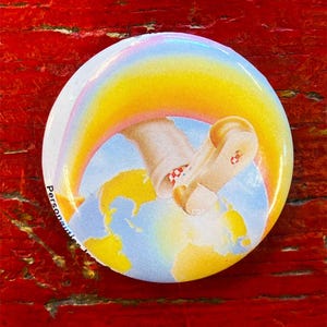 May include: A round button with a colorful image of a hand holding a trumpet, a rainbow, and a globe. The text "Person..." is visible on the left side of the button.