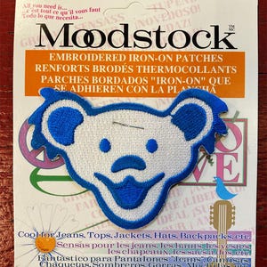 May include: White iron-on patch with a blue smiling bear face. The patch is on a white card with the text "Embroidered Iron-On Patches" and "Cool for Jeans, Tops, Jackets, Hats, Backpacks, etc."