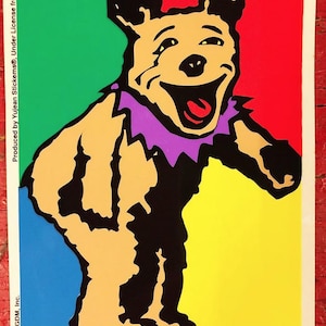May include: A colorful sticker featuring a cartoon bear with a purple collar. The bear is standing on a background of red, green, yellow, and blue.