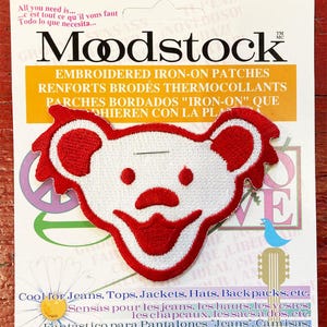 May include: Red and white embroidered iron-on patch of a smiling bear with a red nose. The patch is on a white card with the text "Modstock Embroidered Iron-On Patches" and instructions for use in English, French, and Spanish.