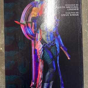 May include: A collectible statue of Dawn, a character from the comic book series "The Darkness", by Dynamite Entertainment. The statue is made of resin and features Dawn in a dynamic pose, holding a sword and standing on a base with a skull design. The statue is painted in a variety of colors, including red, blue, and green.