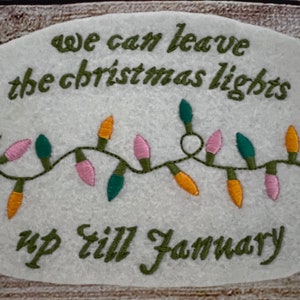 May include: Embroidered felt patch with the text "We can leave the Christmas lights up till January" and a string of pink, orange, and green lights.