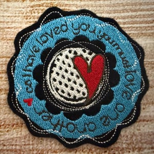 May include: Blue and black embroidered patch with a white and black polka dot heart with a red heart inside. The text on the patch reads "can't have loved you more to love you less".