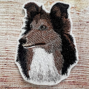 May include: Embroidered patch of a brown and black dog with white fur on its chest. The dog is looking to the left and has a serious expression.